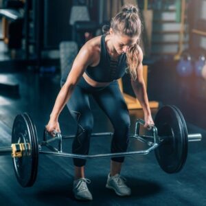 Kvinna lyfter en skivstång med trap bar på ett gym
