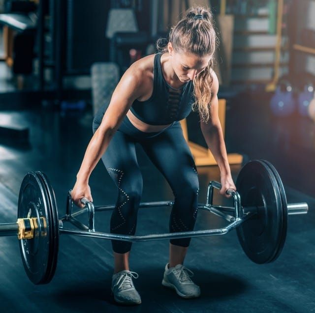 Kvinna lyfter en skivstång med trap bar på ett gym