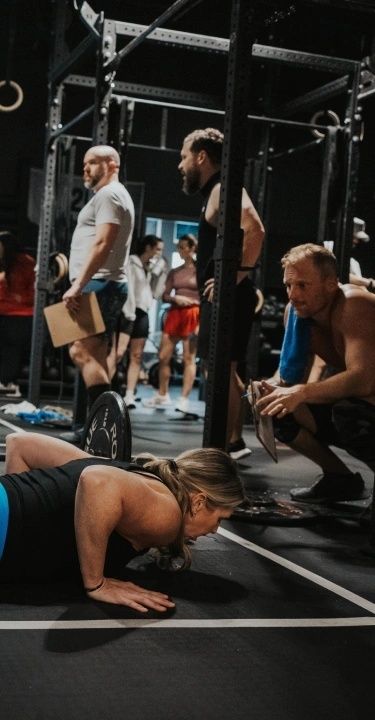 Gruppträning med coacher som stöttar deltagare under ett gympass